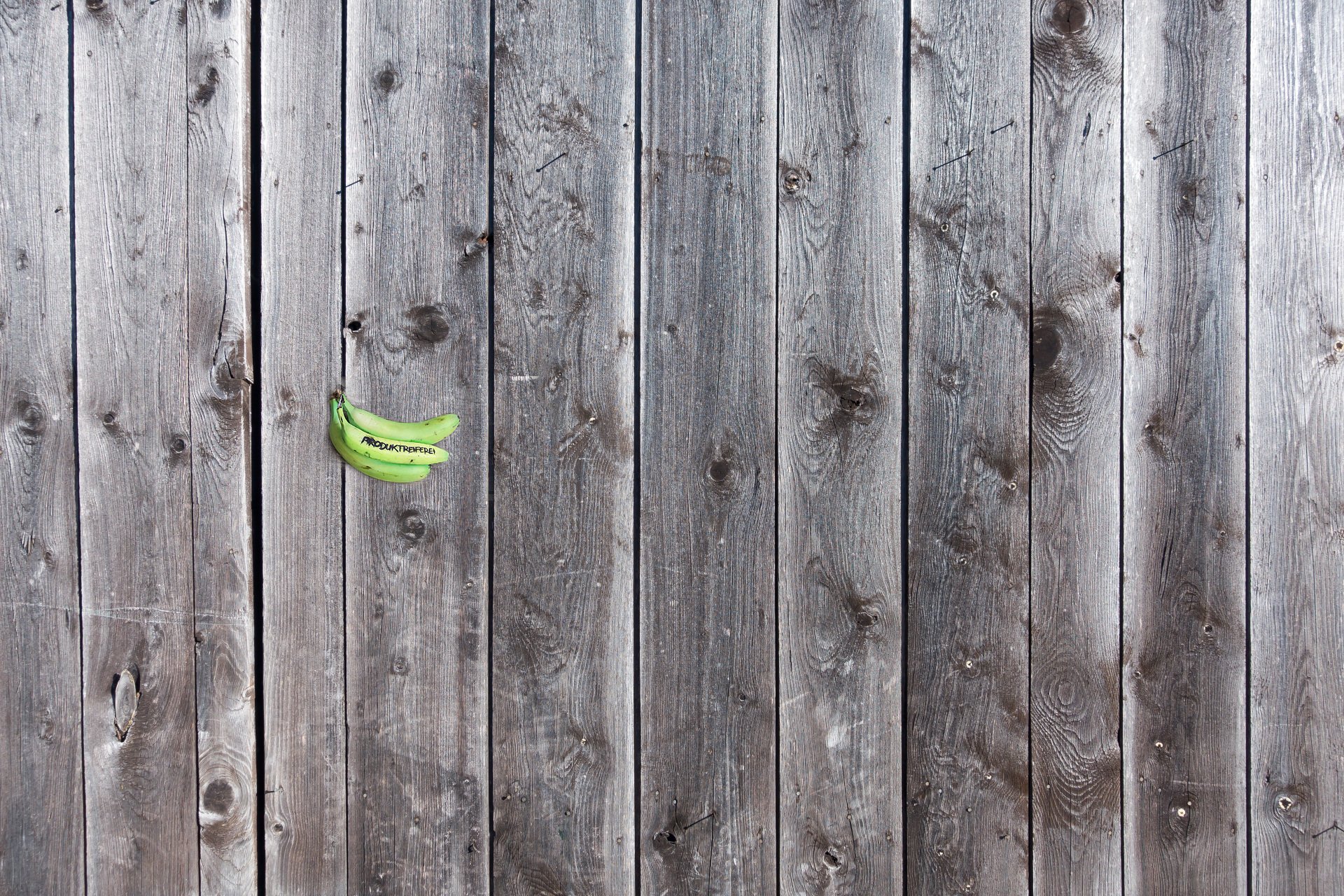 3 grüne Bananen. Eingeritzt ist das Wort 